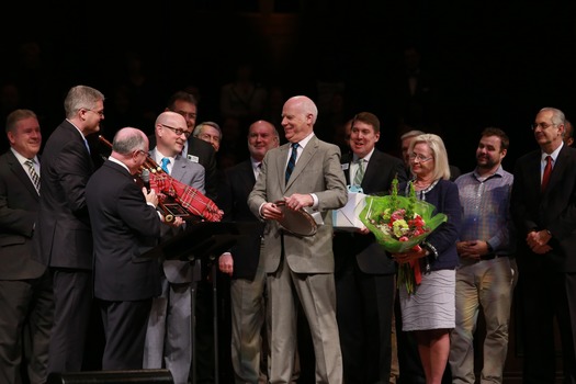 Sam Jacks and John Tartt (left), surrounded by Calvary staff pastors and leadership, presented bagpipes, a silver plaque, and flowers to Dr. John H. Munro (center) and his wife, Gudny Munro.