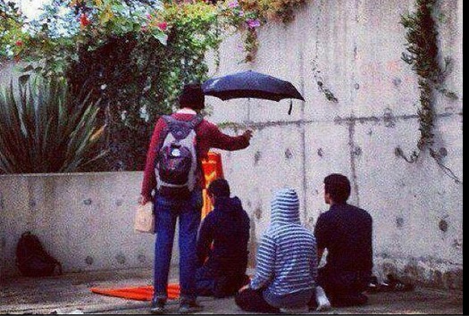 Young atheist holding umbrella over praying Muslims in Taksim