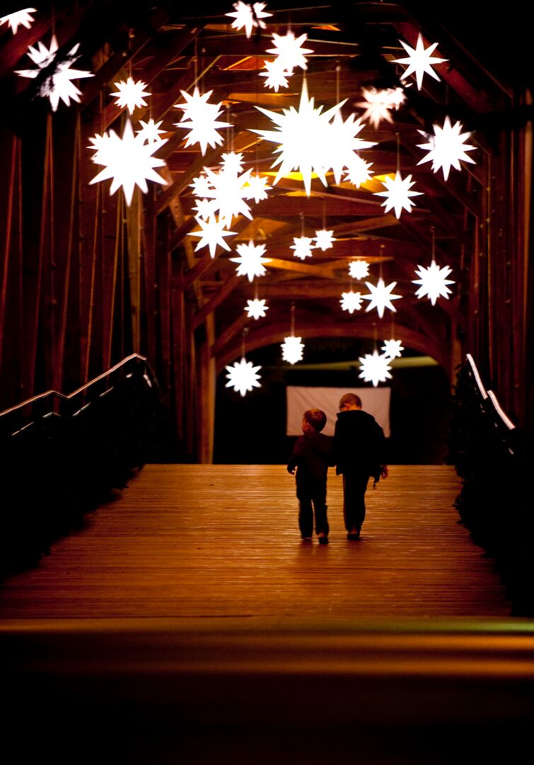 Moravian stars delight vistors while strolling across a covered bridge in Old Salem