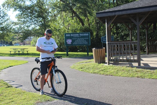 Ryan M by trailhead sign with phone