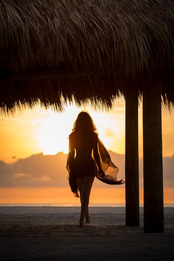 Sunset Silhouette Woman Walking under Cabana on Beach