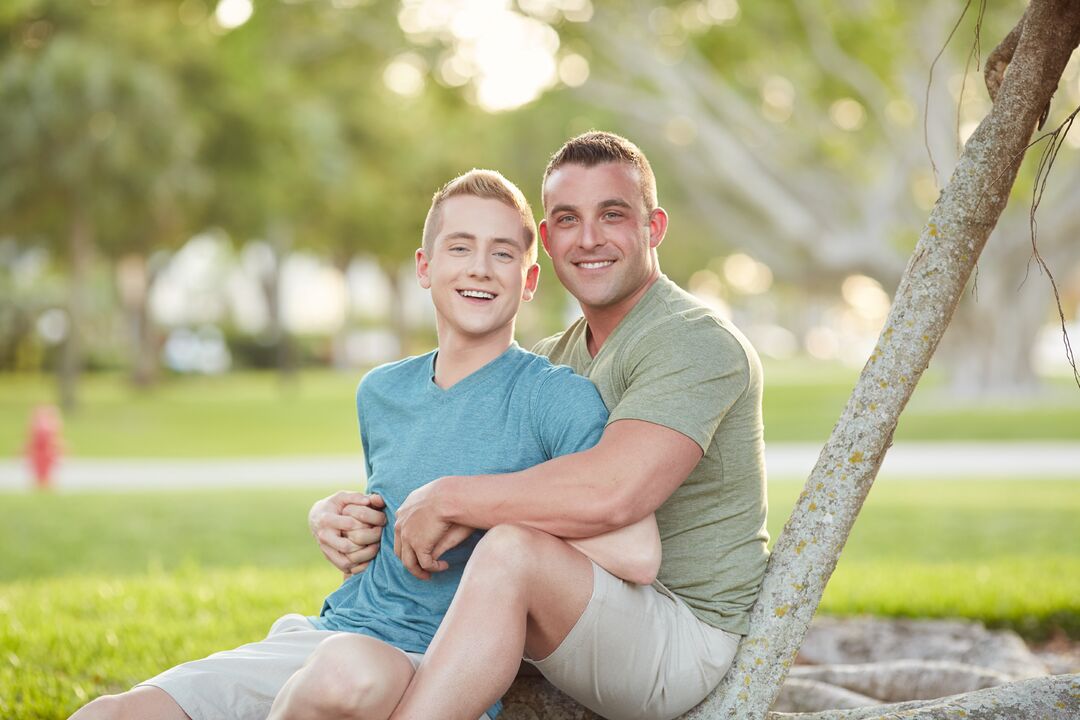 LGBTQ - Couple embracing each other next to tree - close up front horizontal